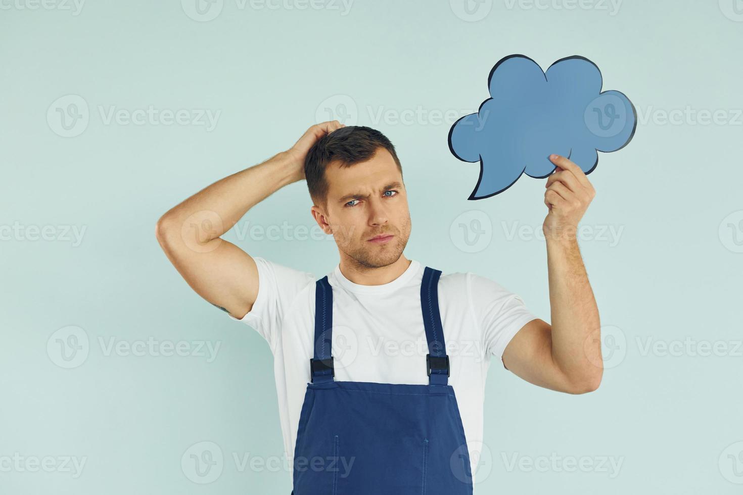 In blue uniform. Man standing in the studio with empty signs for the text photo