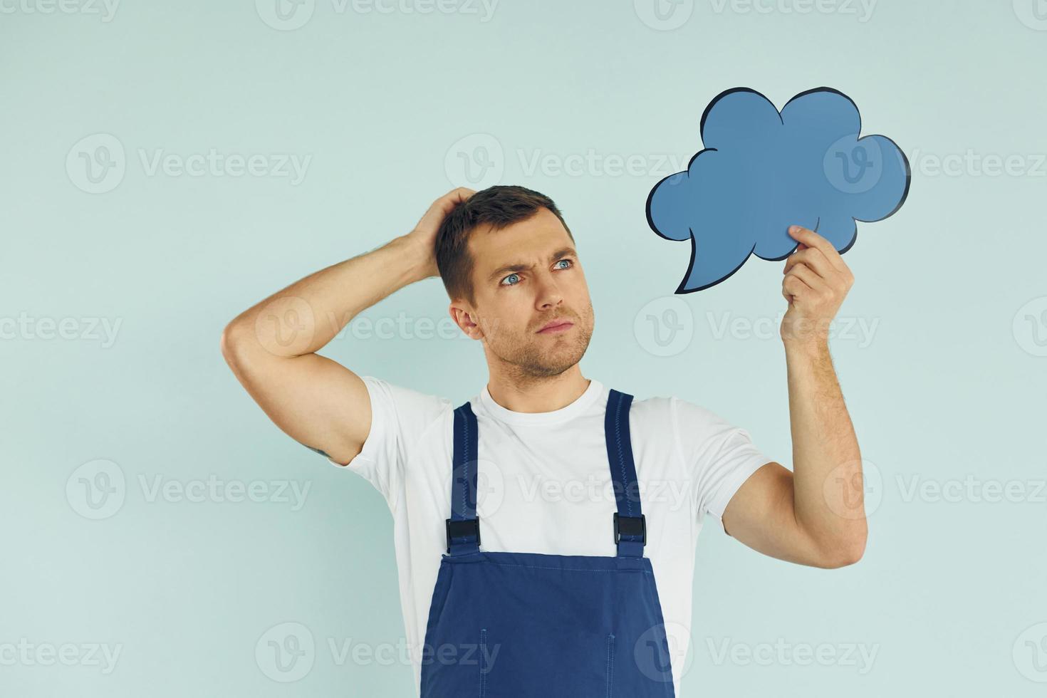 In blue uniform. Man standing in the studio with empty signs for the text photo