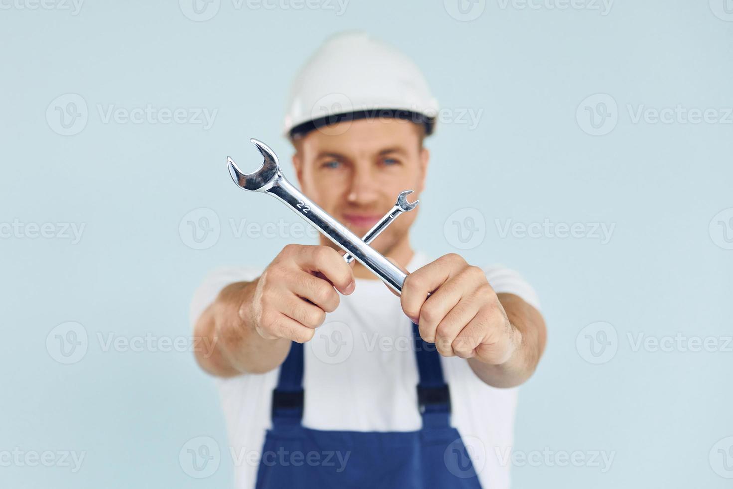 Worker in uniform and hard hat standing in the studio with equipment photo