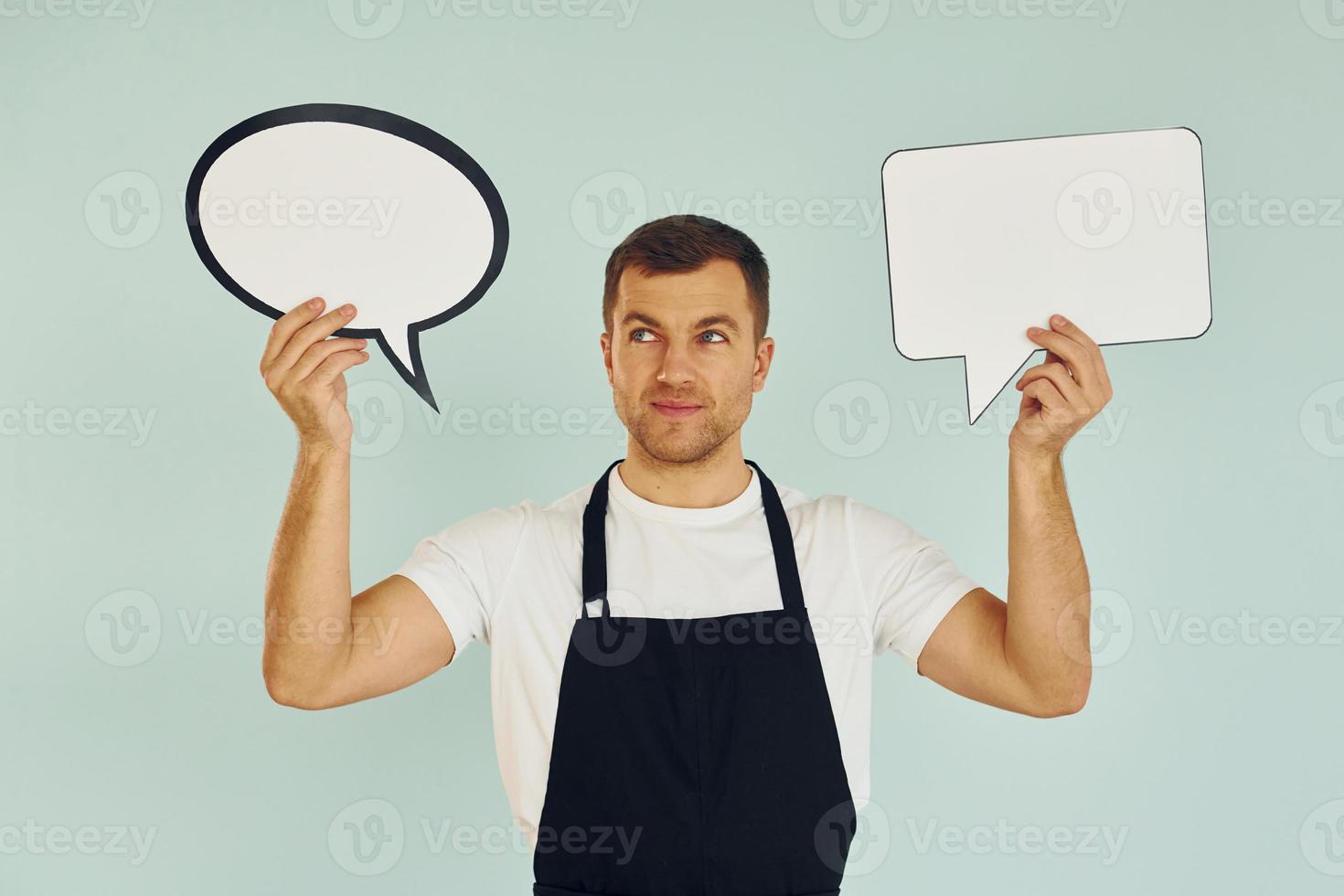 Hard choice between two ideas. Man standing in the studio with empty signs for the text photo