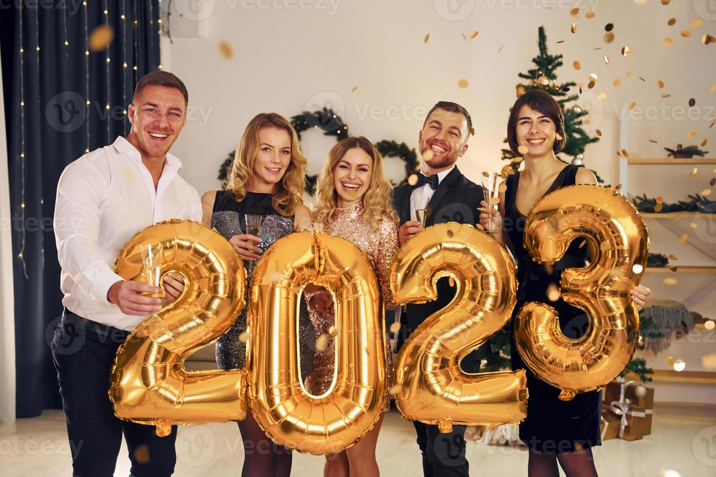 sosteniendo globos con el número 2023. grupo de personas tienen una fiesta de año nuevo en el interior juntos foto