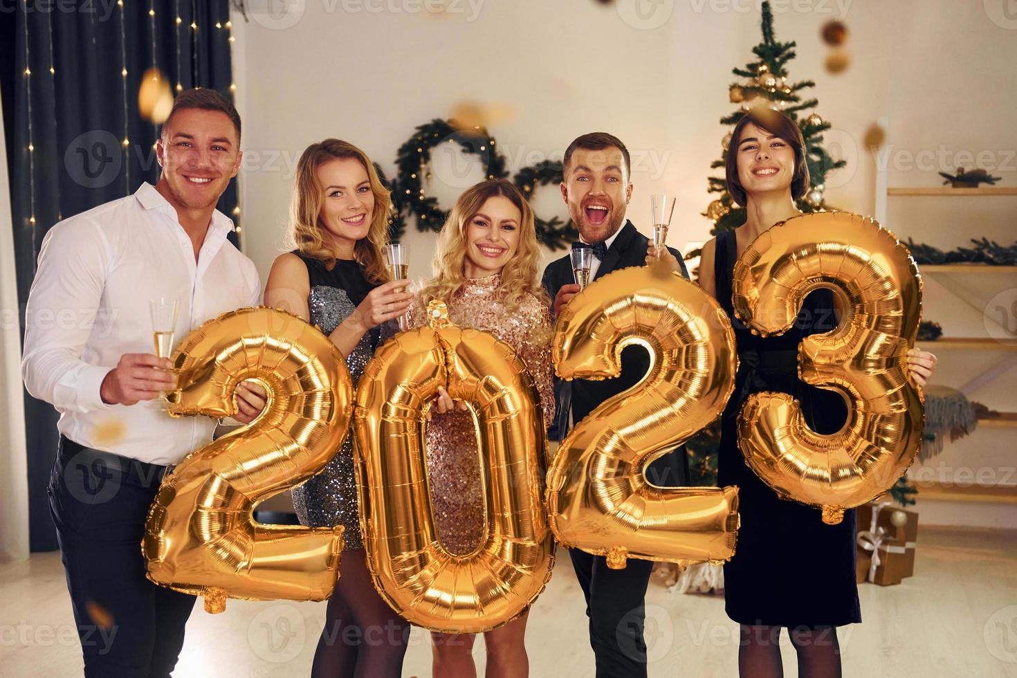 sosteniendo globos con el número 2023. grupo de personas tienen una fiesta de año nuevo en el interior juntos foto