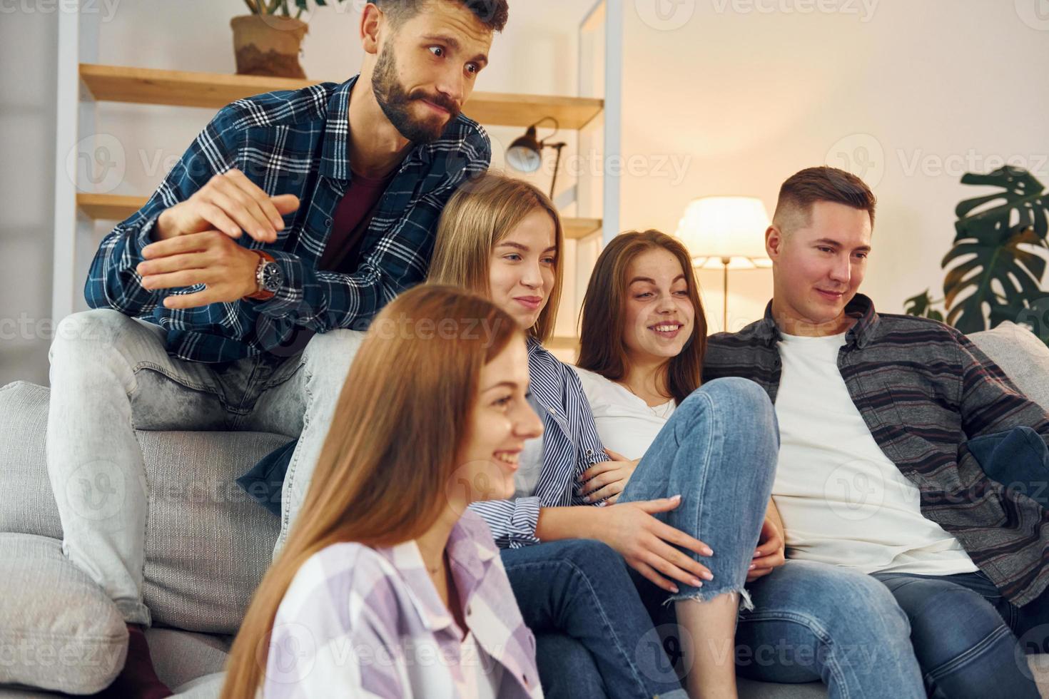 Sitting on the sofa. Group of friends have party indoors together photo