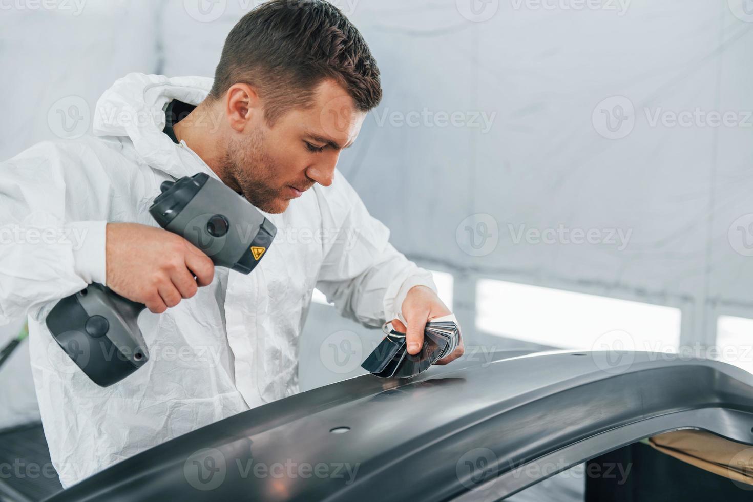 Working with car surface. Man in uniform is working in the auto service photo