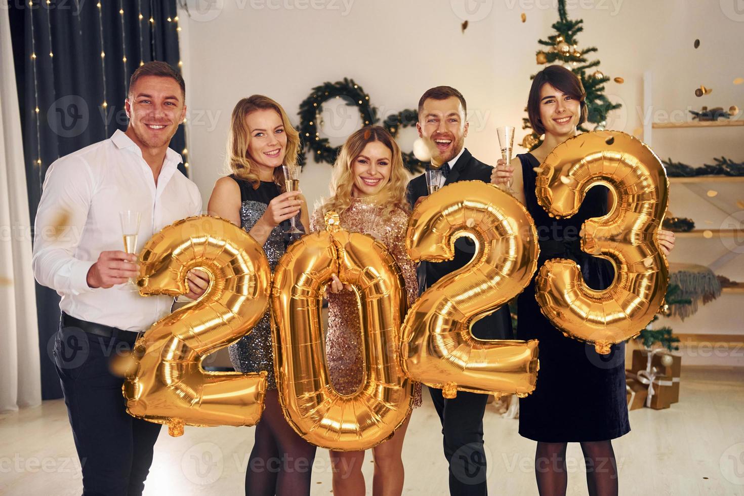 sosteniendo globos con el número 2023. grupo de personas tienen una fiesta de año nuevo en el interior juntos foto