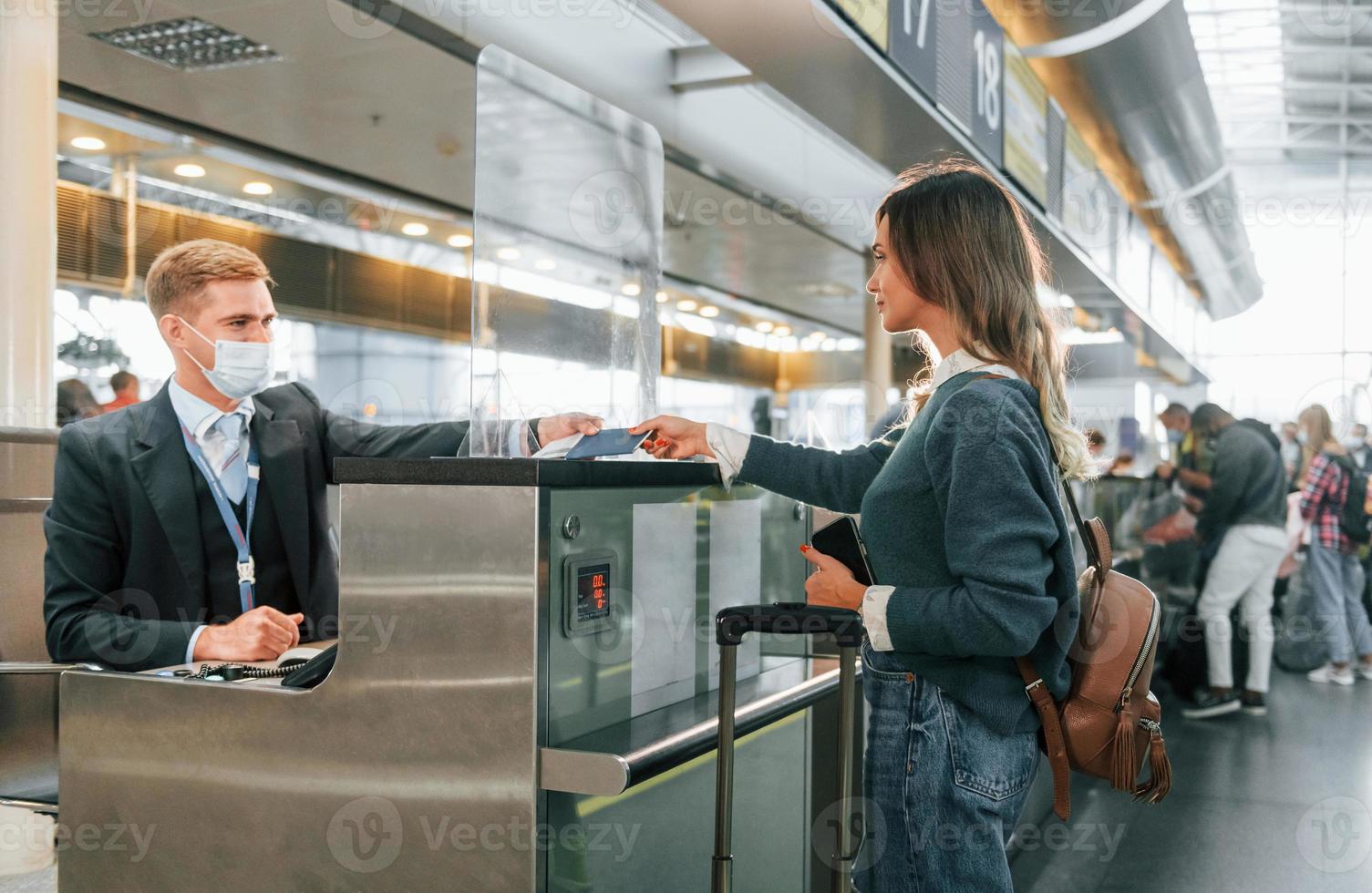 de pie junto a la mesa con el empleado. joven turista está en el aeropuerto durante el día foto