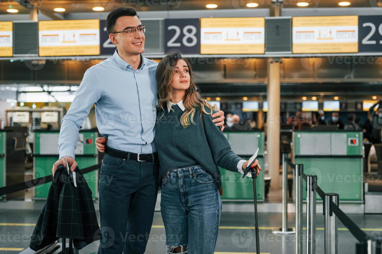 Embracing each other. Young couple is in the airport together photo