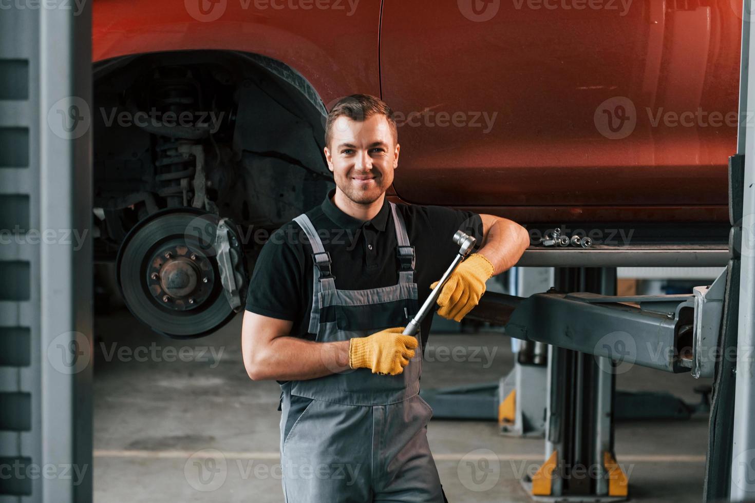 Professional service. Man in uniform is working in the auto service photo