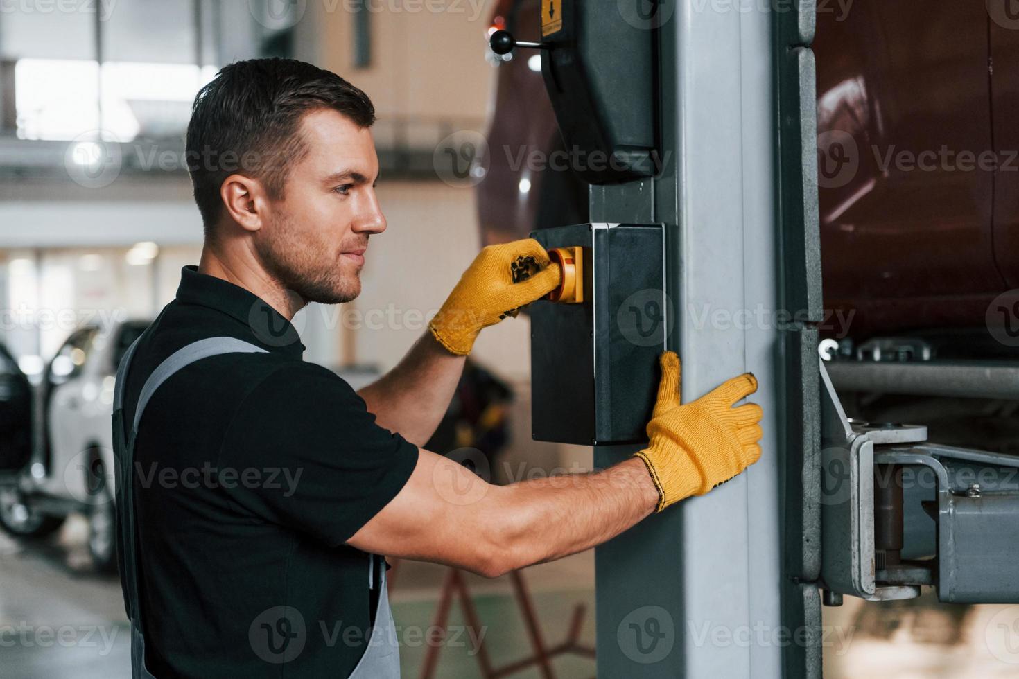 At daytime. Man in uniform is working in the auto service photo