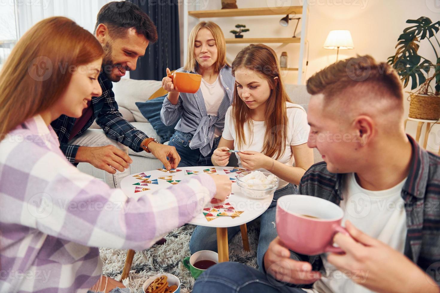 Focused at puzzle game. Group of friends have party indoors together photo