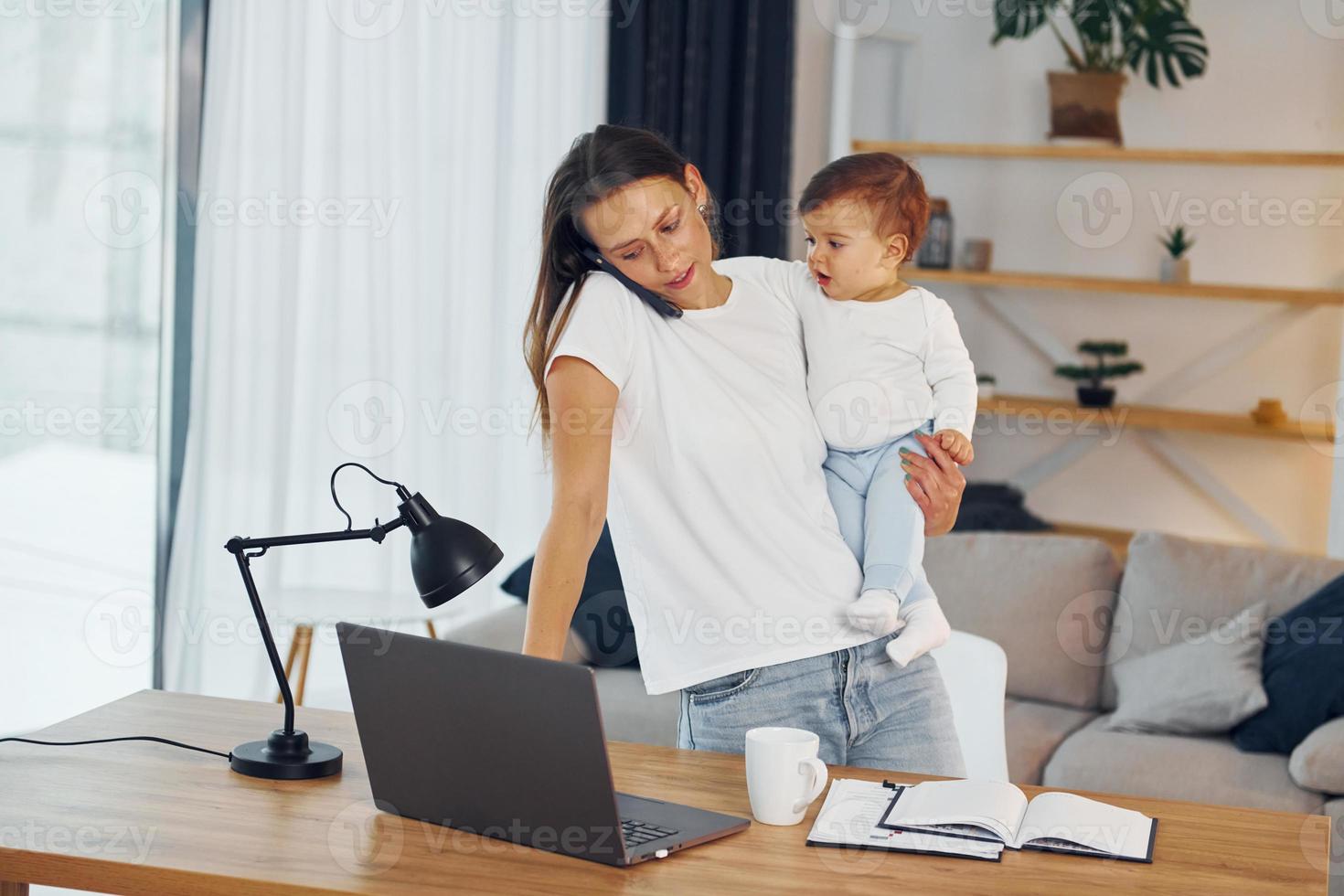 Using laptop. Mother with her little daughter is at home together photo