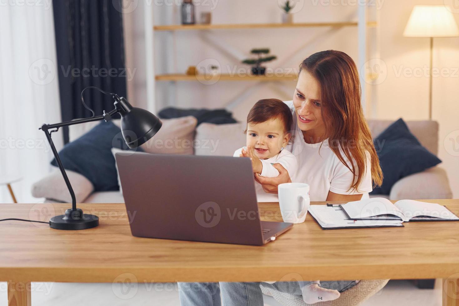 viendo películas usando una computadora portátil. madre con su pequeña hija está en casa juntos foto