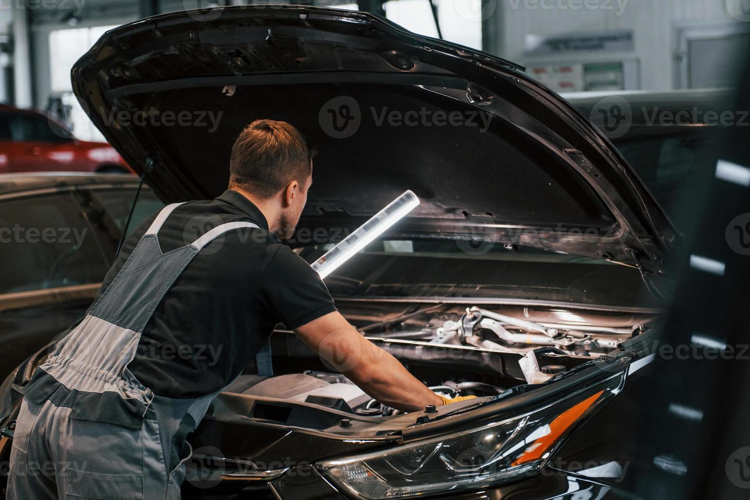 Side view. Man in uniform is working in the auto service photo