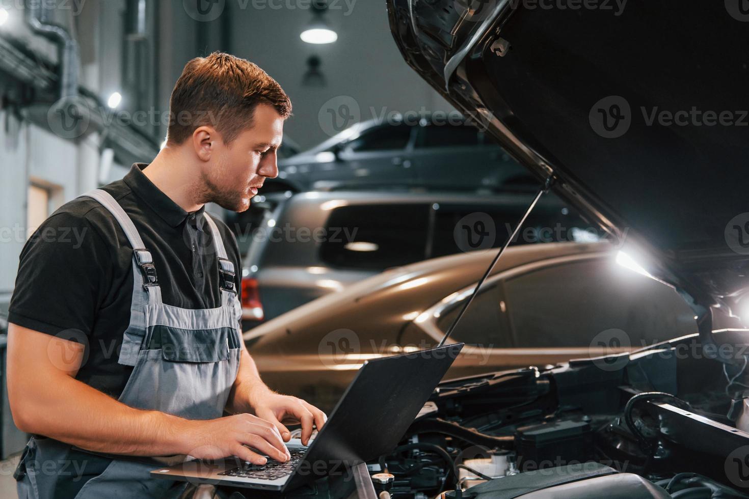 Side view. Man in uniform is working in the auto service photo