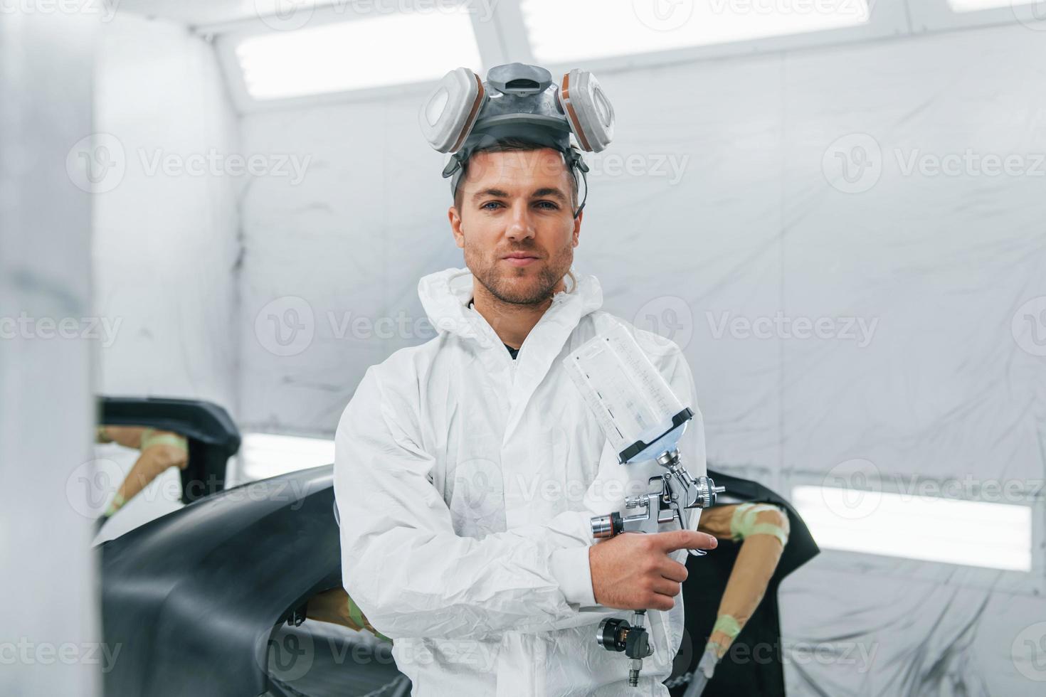 Ready for the painting. Man in uniform is working in the auto service photo