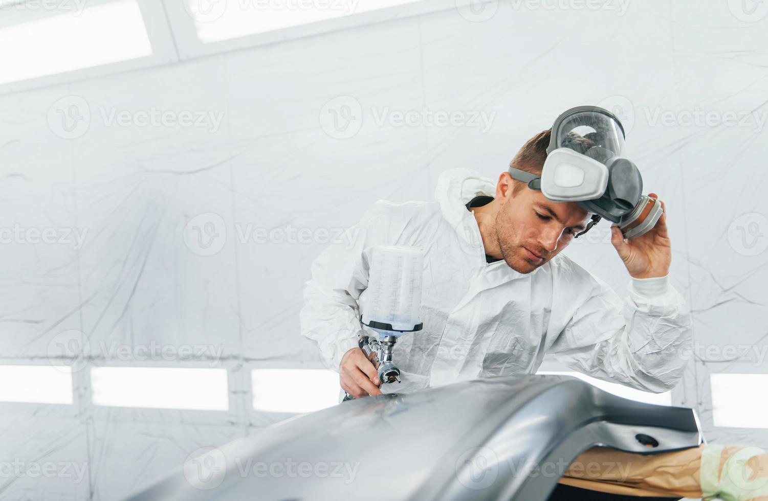 Painting the car. Man in uniform is working in the auto service photo