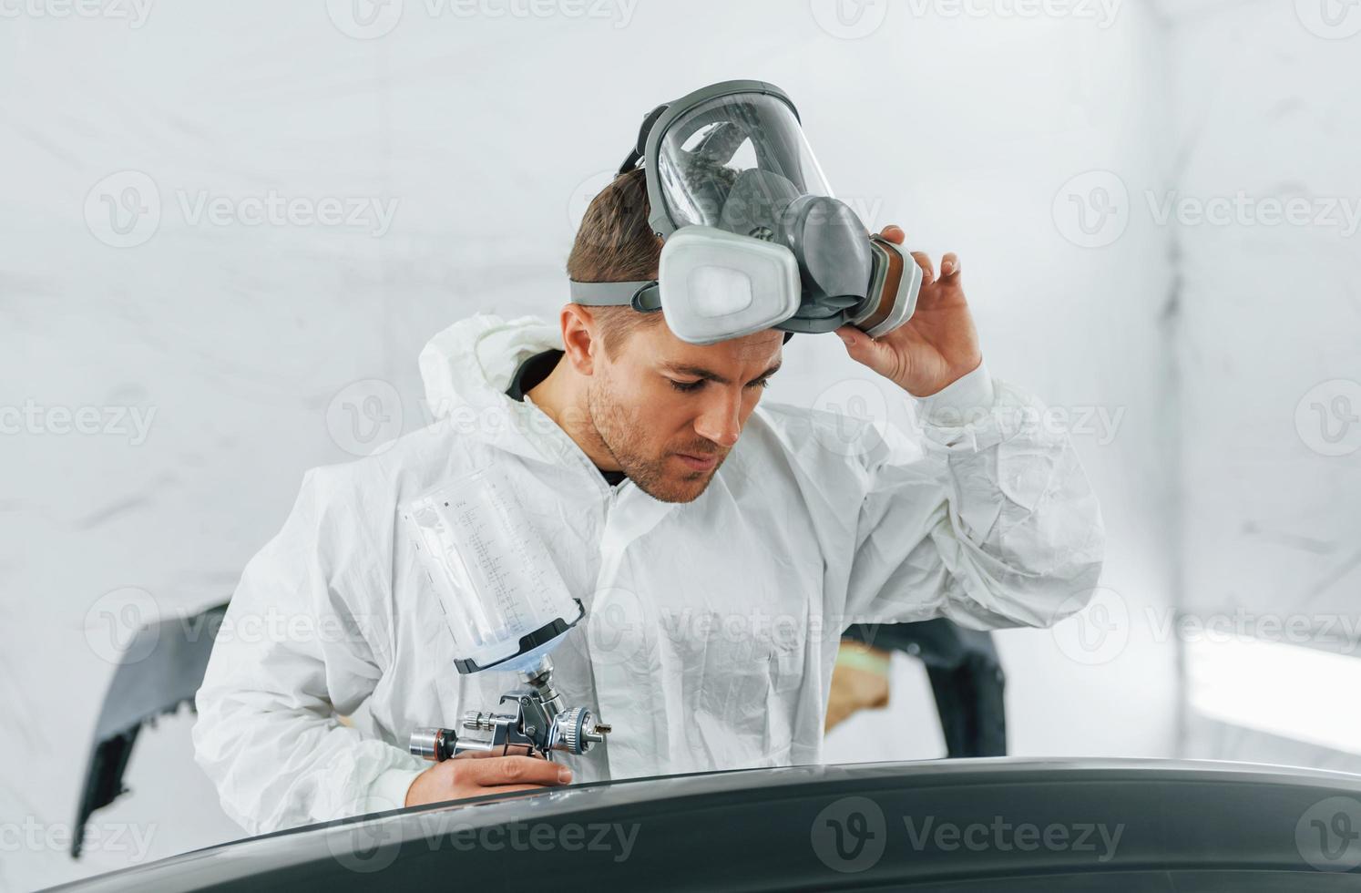 Painting the car. Man in uniform is working in the auto service photo