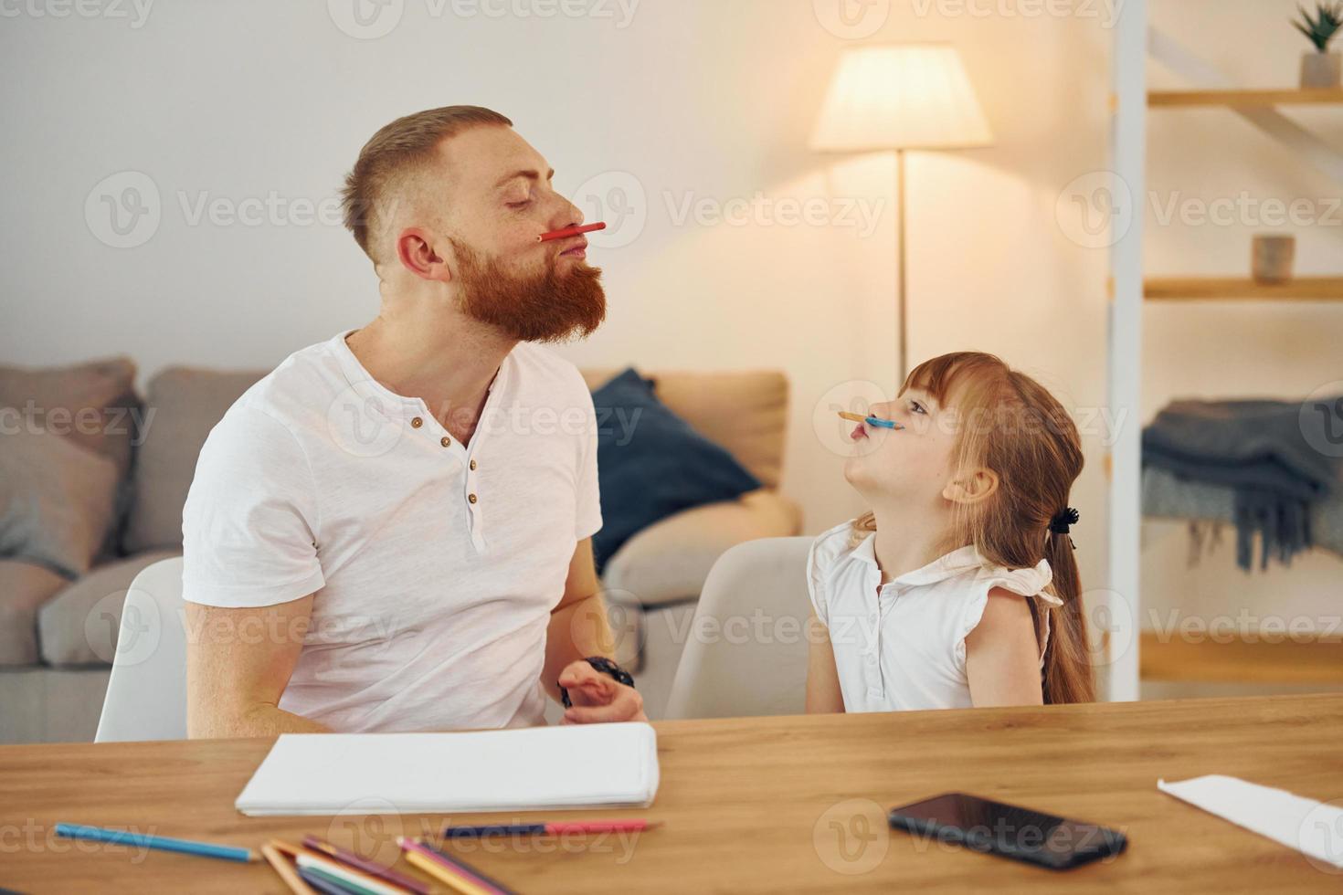 Little girl sitting by the table. Father with his little daughter is at home together photo