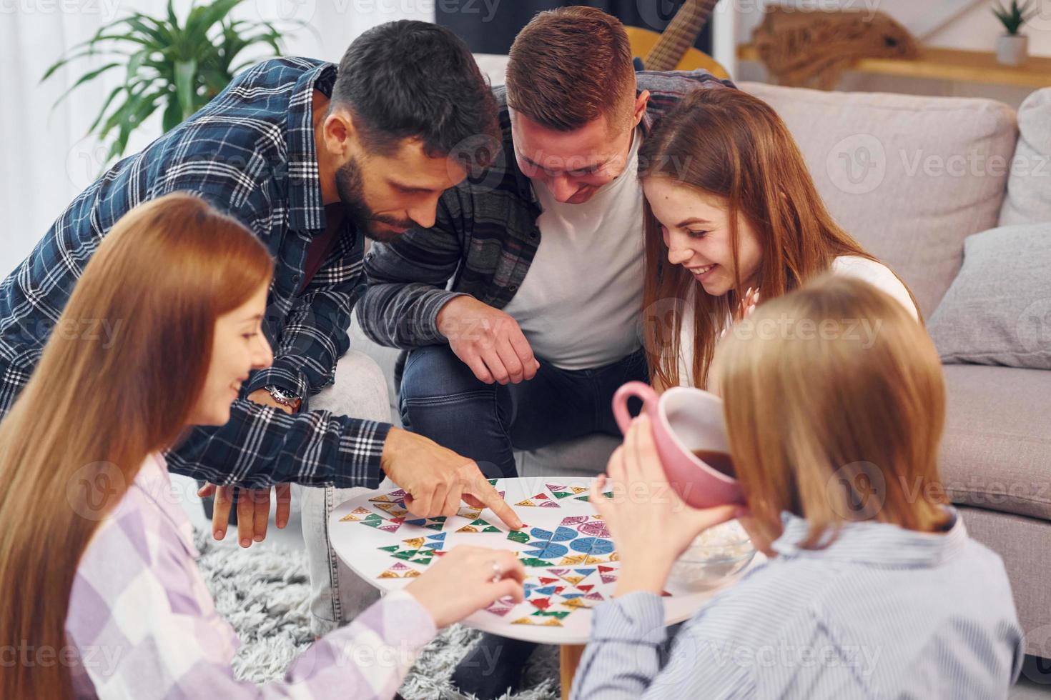 Playing puzzle game. Group of friends have party indoors together photo