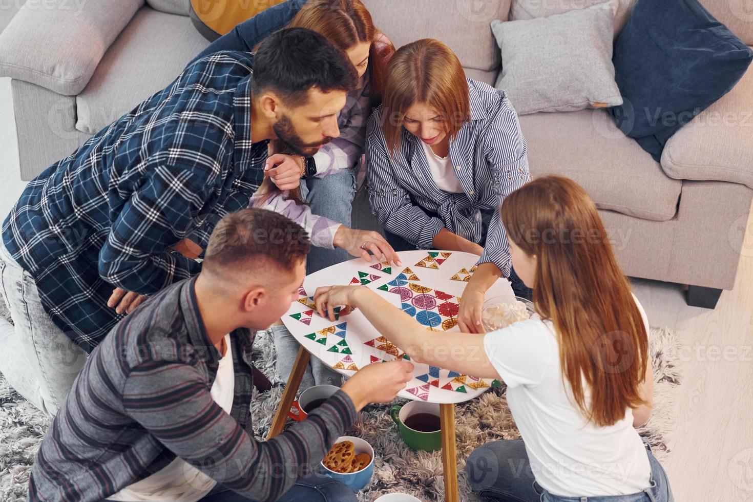 Playing puzzle game. Group of friends have party indoors together photo
