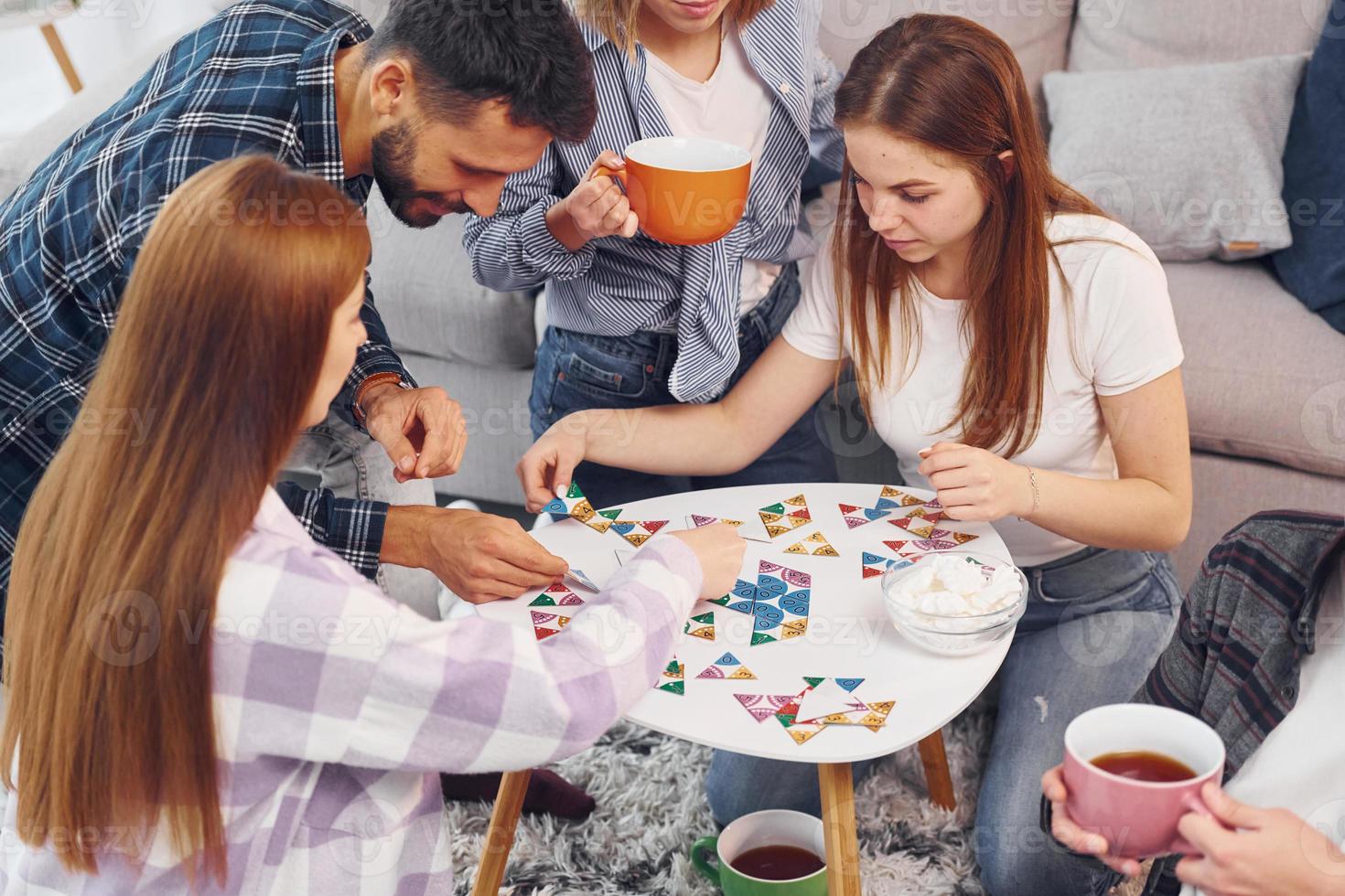 jugando un juego de rompecabezas. grupo de amigos tienen una fiesta en el interior juntos foto