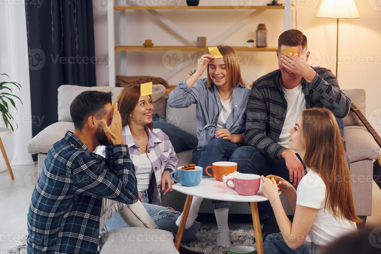Playing who am I game. Group of friends have party indoors together photo