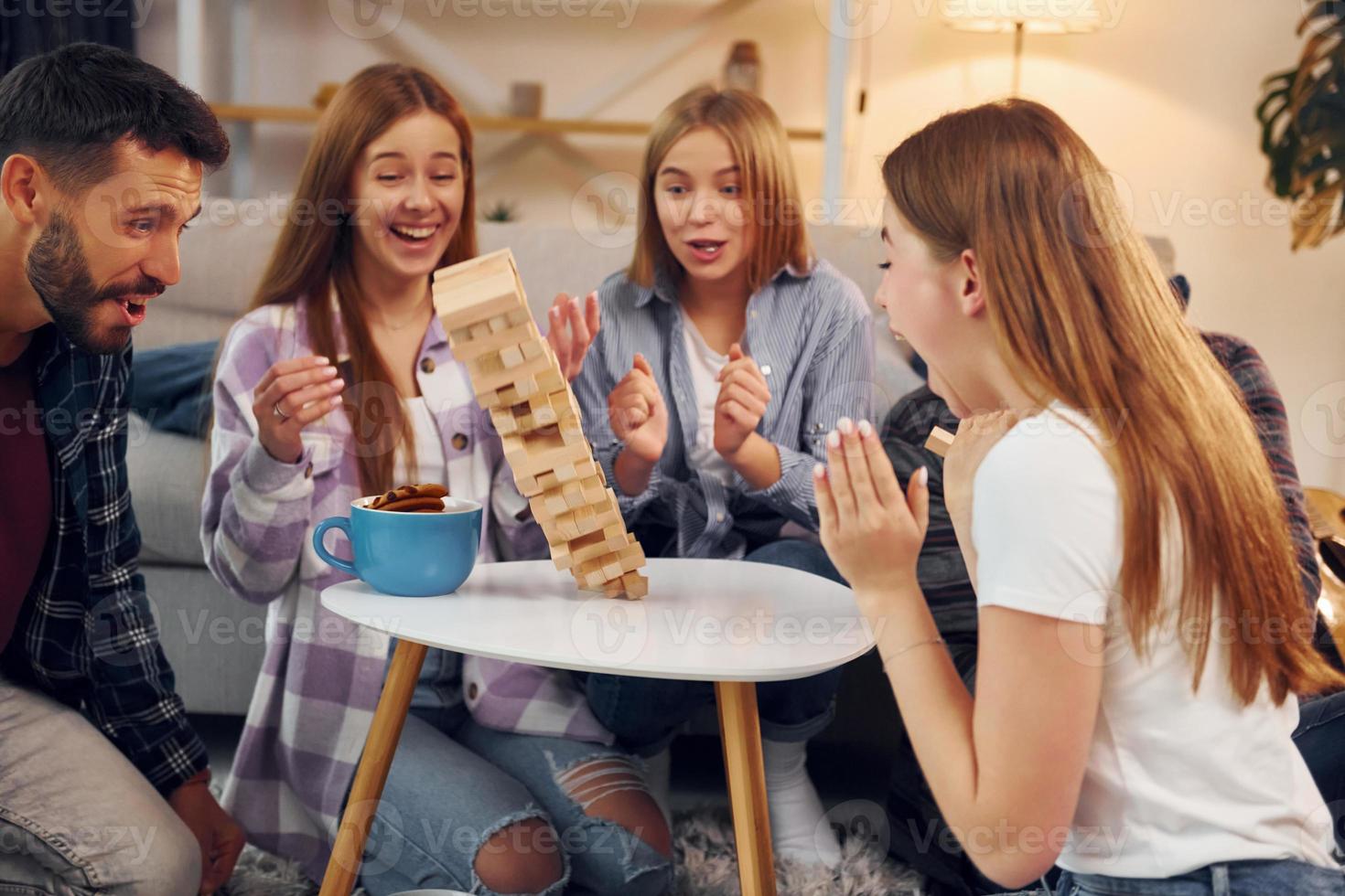 Wooden tower has fallen. Group of friends have party indoors together photo