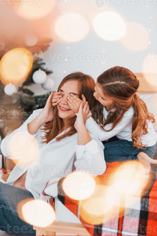 Having fun. Mother with her little daughter is having fun indoors on the bed photo