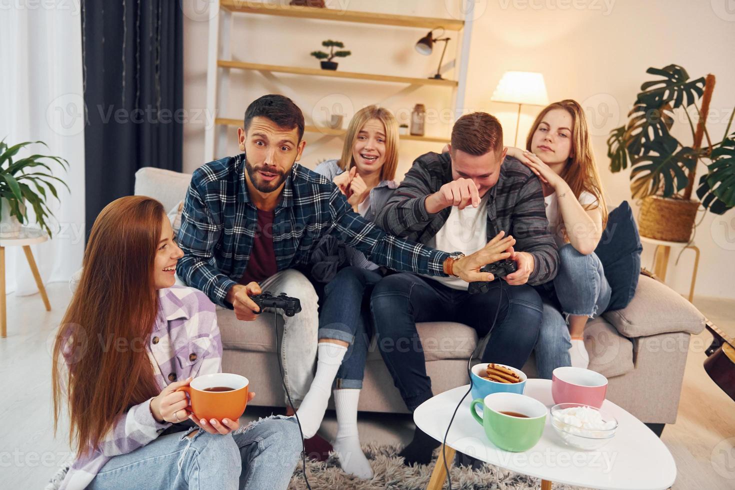 Playing video game. Group of friends have party indoors together photo