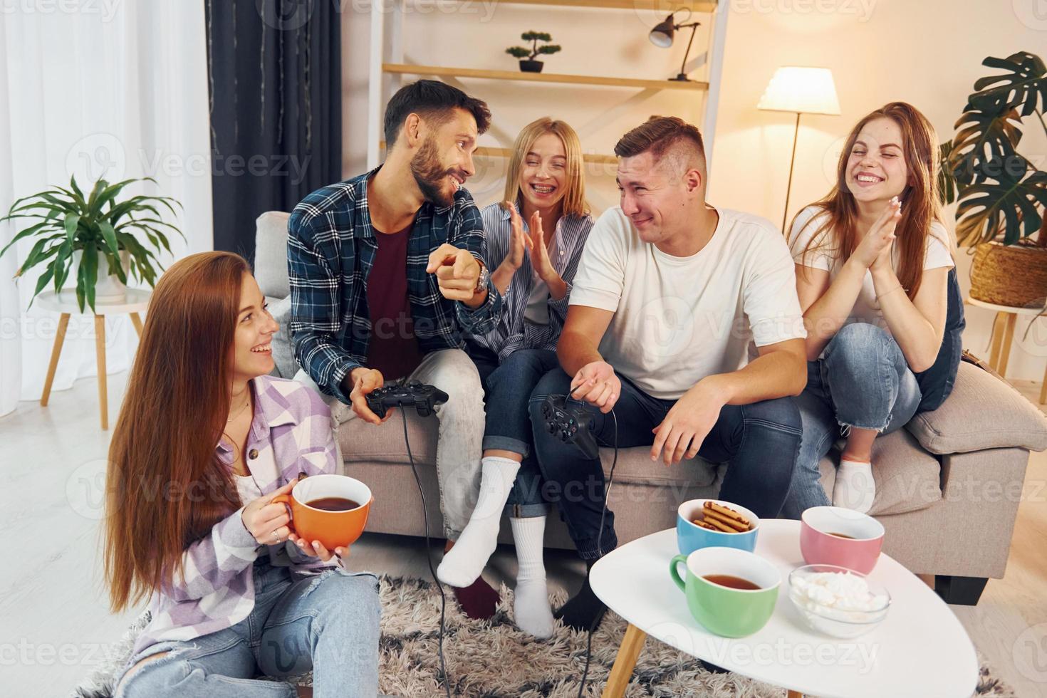 Spending weekend together. Group of friends have party indoors together photo