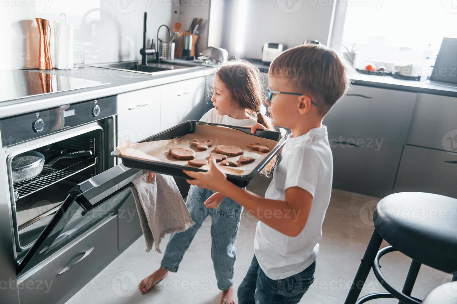 Baking food. Little boy and girl preparing Christmas cookies on the kitchen photo