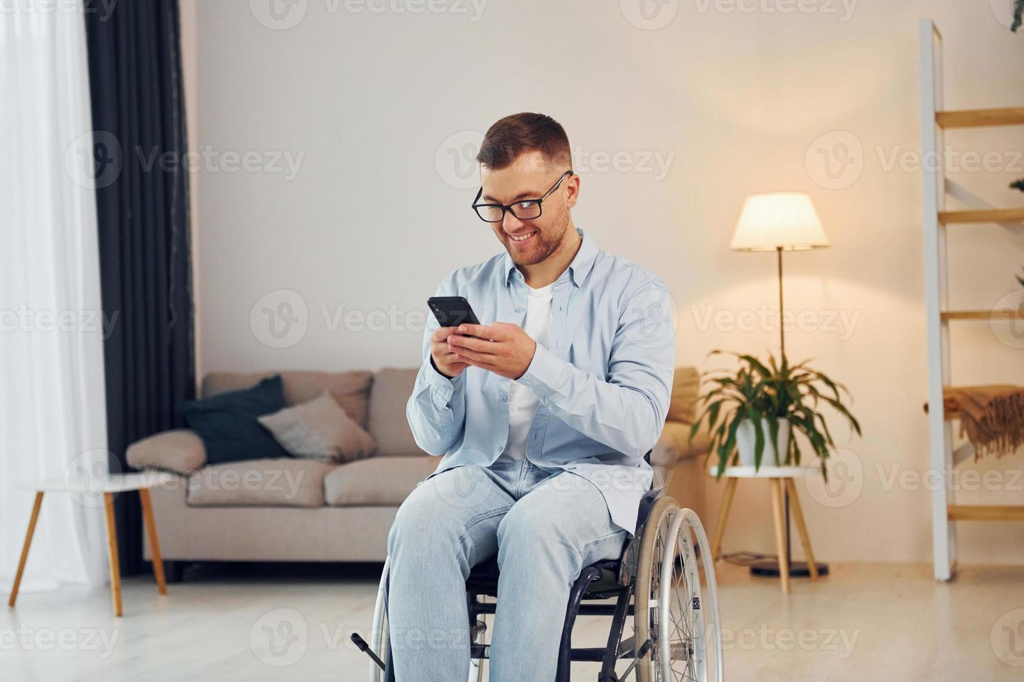 Using phone. Disabled man in wheelchair is at home photo