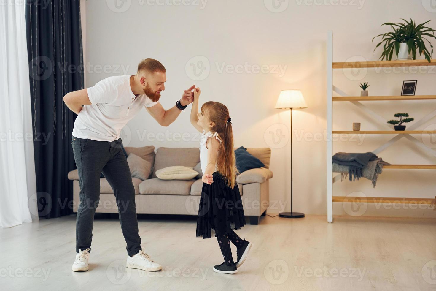 Teaching how to dance. Father with his little daughter is at home together photo