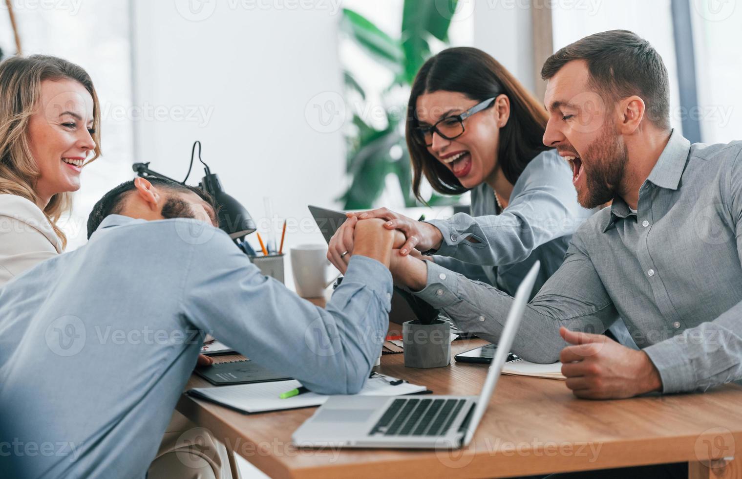 Playing arm wrestling. Group of business people that working on the project in the office photo