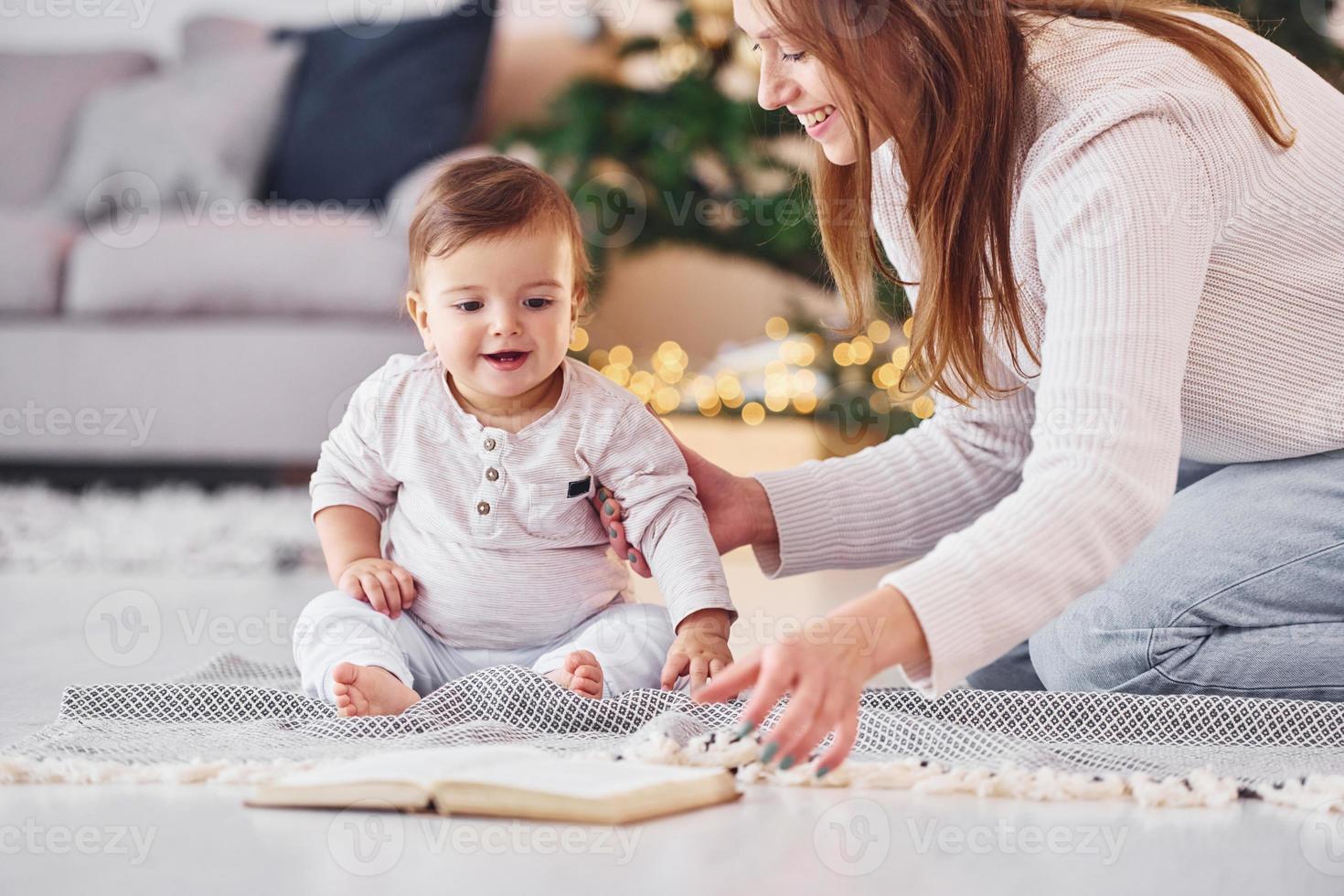 leyendo un libro juntos. madre con su pequeña hija está adentro en casa juntos foto