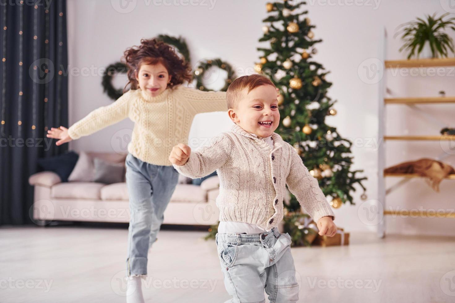 Active time spending. Little brother and sister is at christmas decorated room together photo