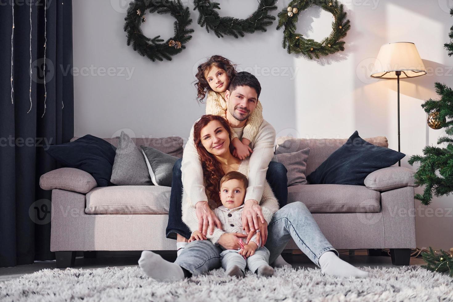 Sitting near sofa. Family celebrating new year with their children at home photo