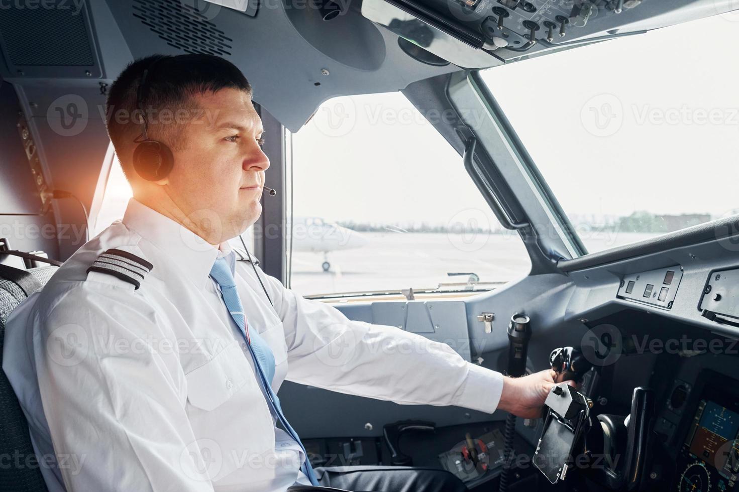 Side view. Pilot in formal wear sits in the cockpit and controls airplane photo