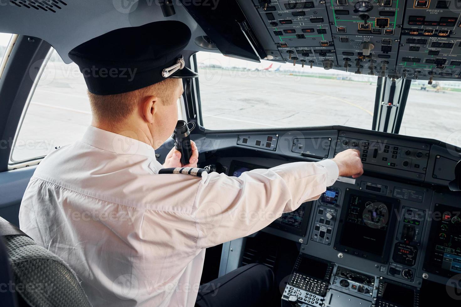 Pilot in formal wear sits in the cockpit and controls airplane photo