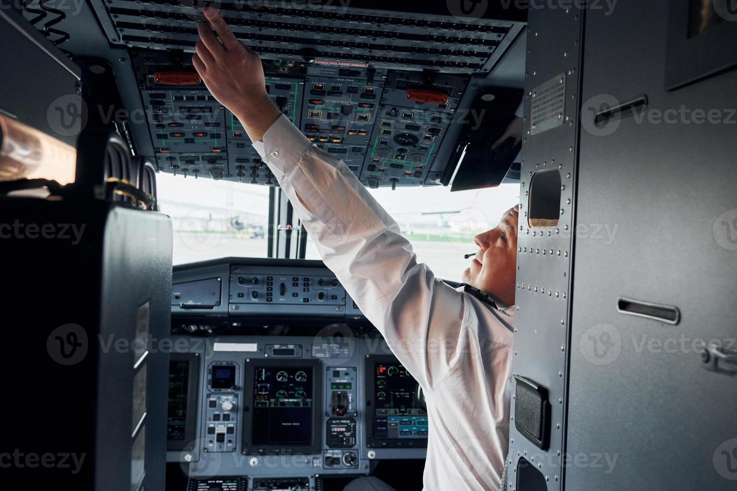 Pilot in formal wear sits in the cockpit and controls airplane photo