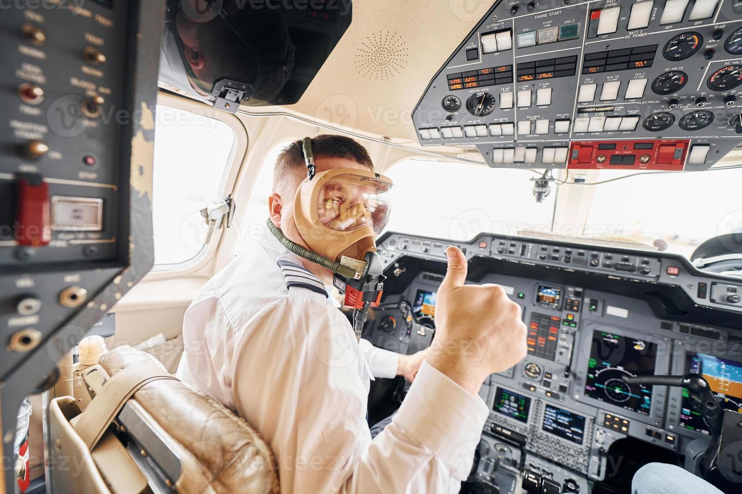 In oxygen mask. Pilot in formal wear sits in the cockpit and controls airplane photo