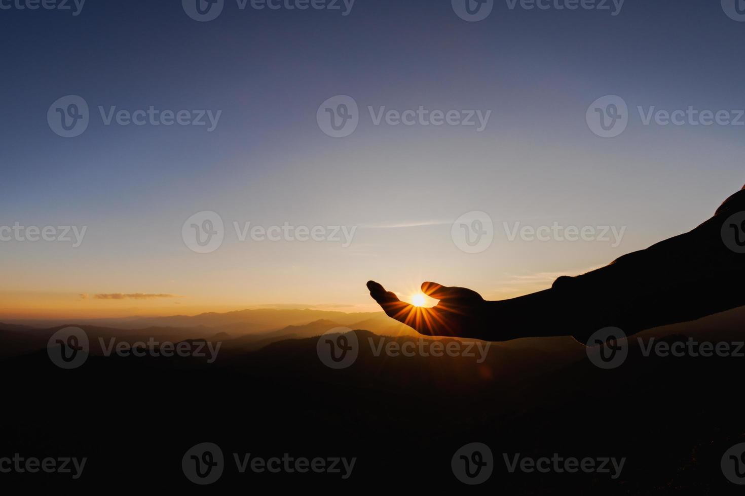 silhouette of man rise hand up praying  on top of mountain and sunset sky abstract background. Freedom and travel adventure concept. photo