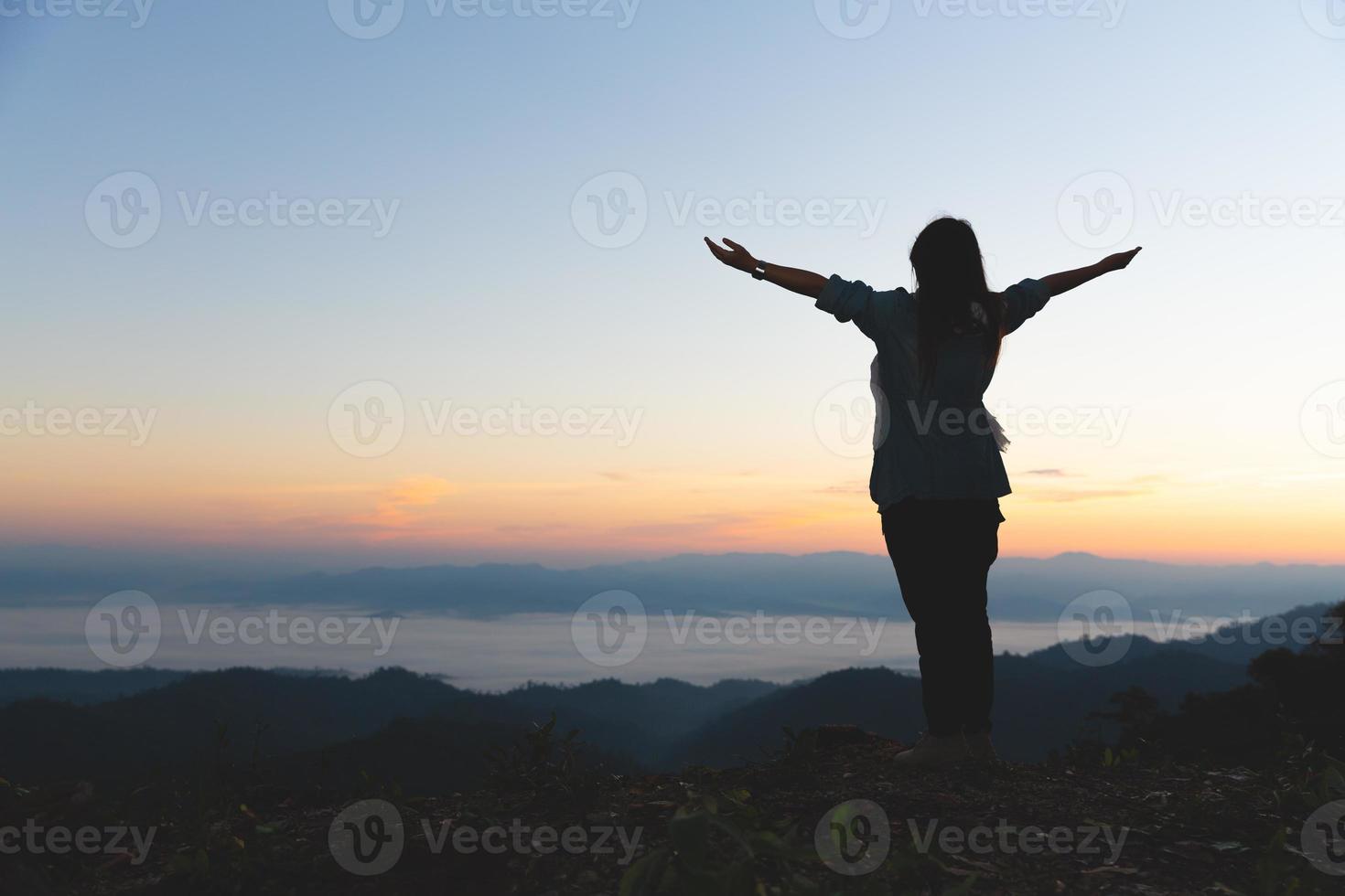 Silhouette of christian young woman praying at sunrise, Freedom and travel adventure concept. Vintage tone filter effect color style. photo