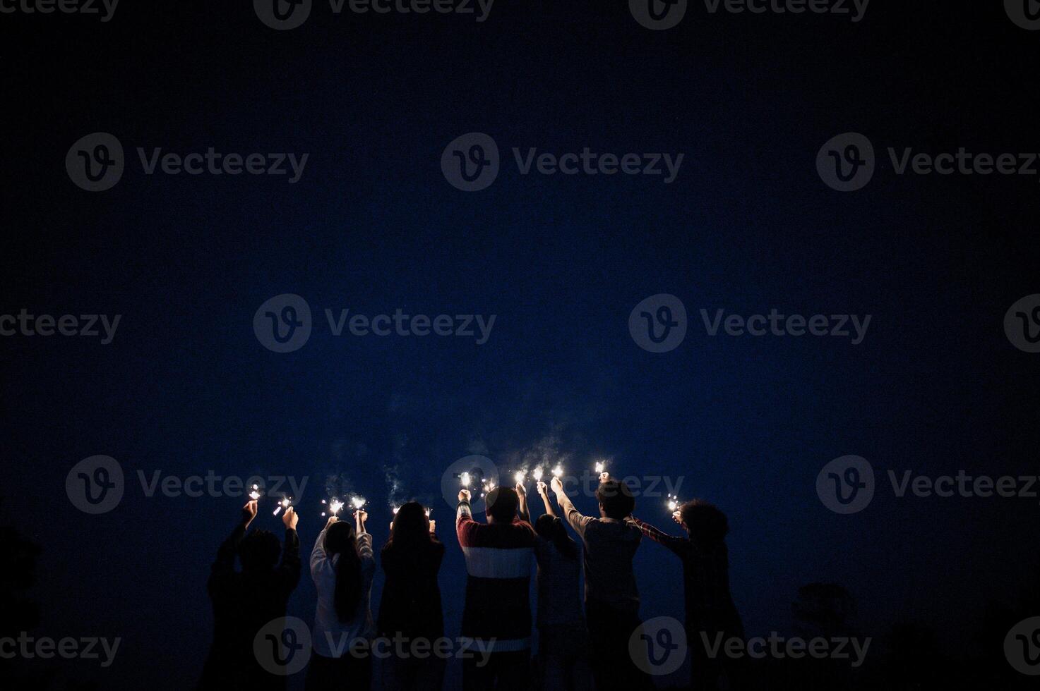 Group of young friends holding and play with fire burning sparklers photo