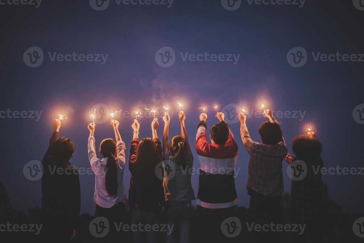 Group of young friends enjoy with burning sparkler in hands together photo