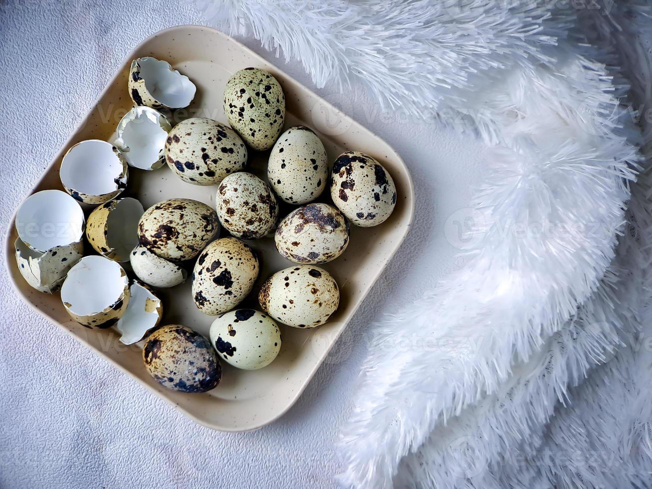 Quail eggs from quail, a collection of quail eggs on a wooden plate with a white feather blanket background photo