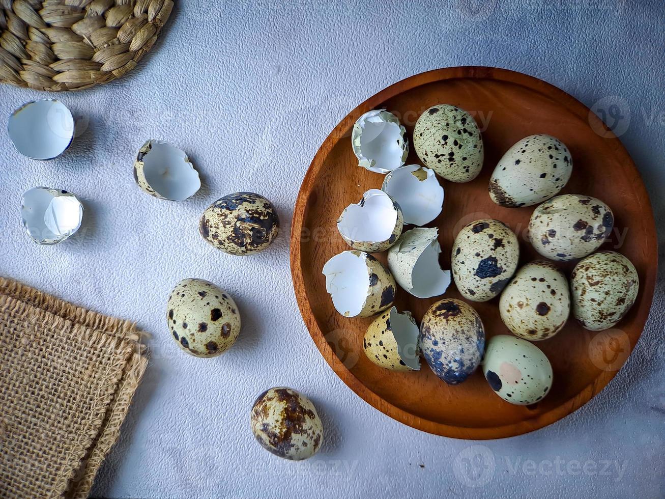 Quail eggs from quail, a collection of quail eggs on a wooden plate against a white wall background photo