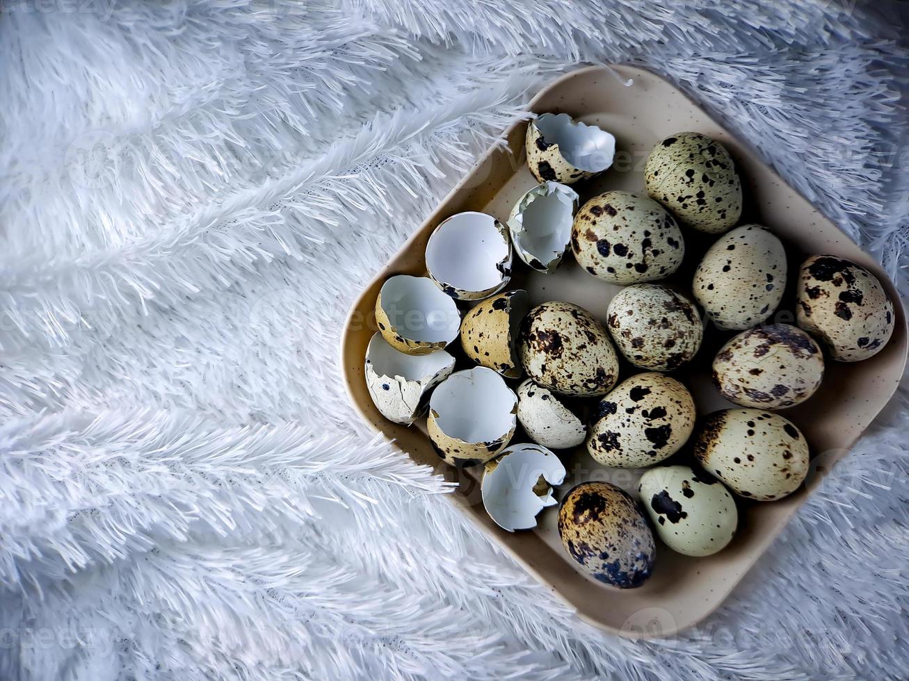Quail eggs from quail, a collection of quail eggs on a wooden plate with a white feather blanket background photo