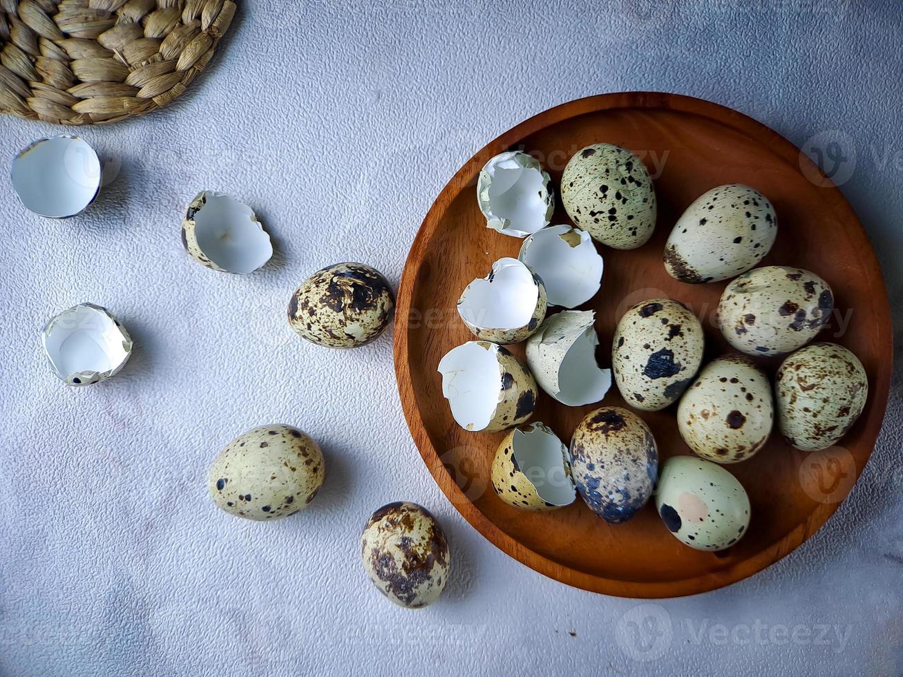 Quail eggs from quail, a collection of quail eggs on a wooden plate against a white wall background photo