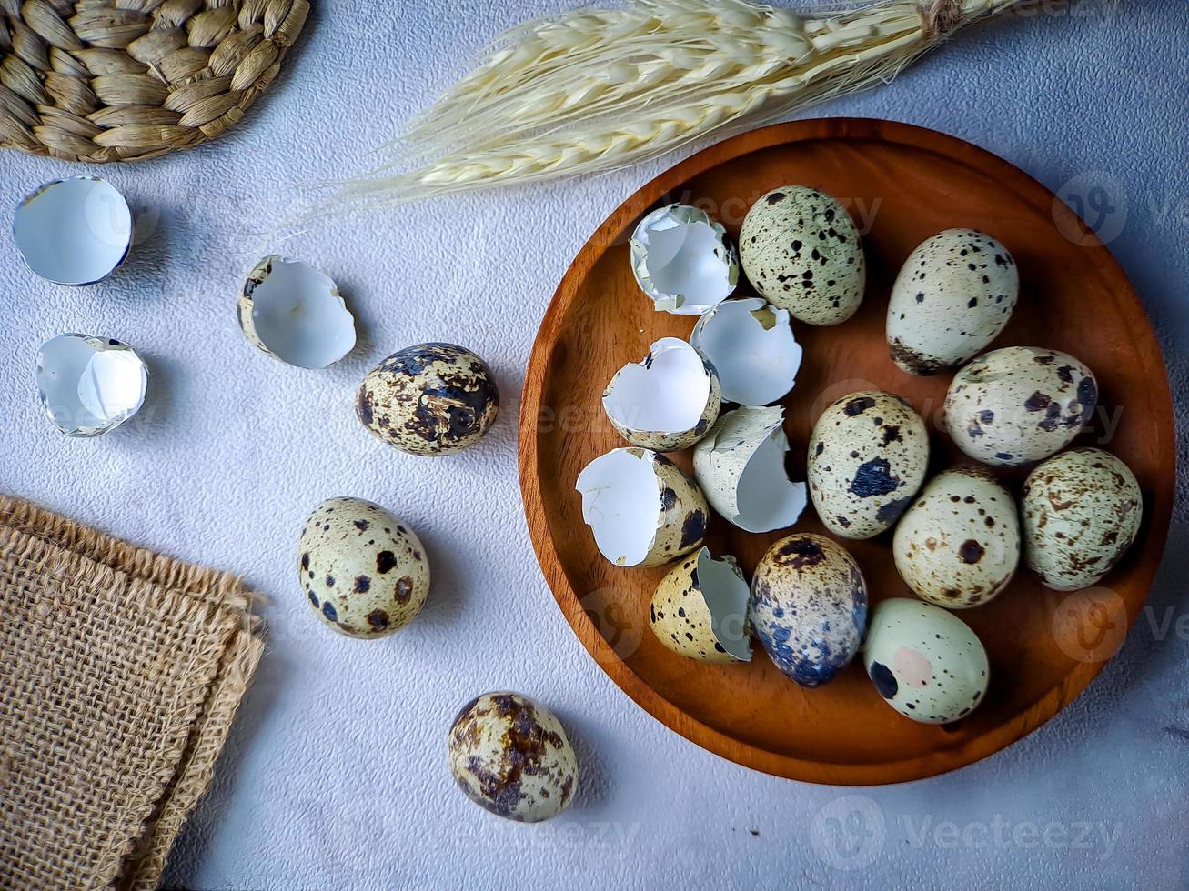 Quail eggs from quail, a collection of quail eggs on a wooden plate against a white wall background photo